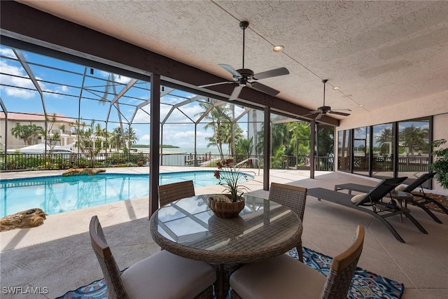 view of swimming pool featuring a patio, glass enclosure, and ceiling fan