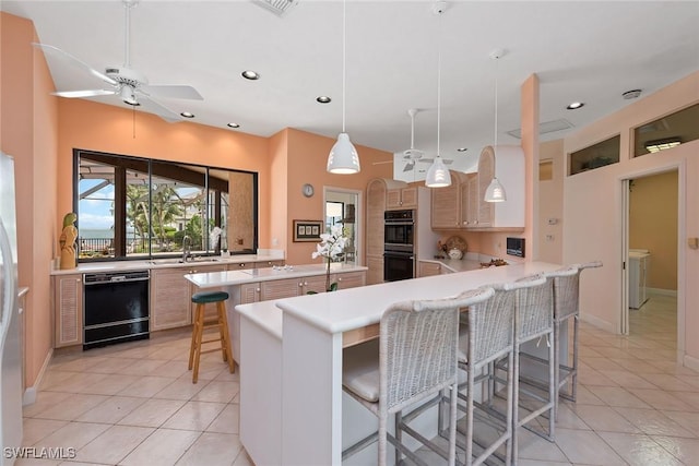 kitchen featuring kitchen peninsula, pendant lighting, a kitchen bar, light tile patterned flooring, and black appliances