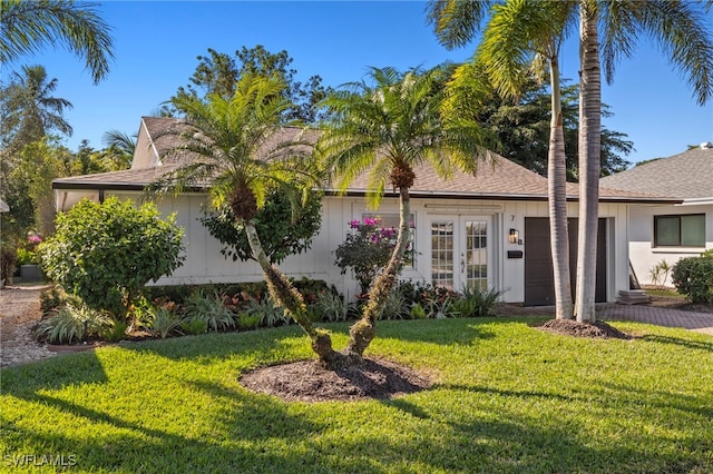 view of front of property with a garage, a front yard, and french doors