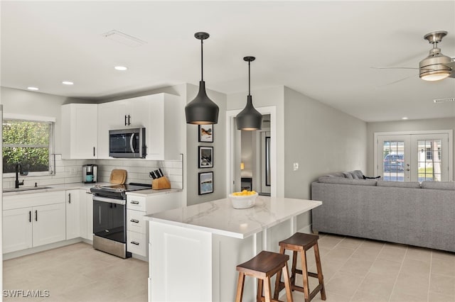 kitchen featuring sink, tasteful backsplash, light stone counters, white cabinetry, and stainless steel appliances