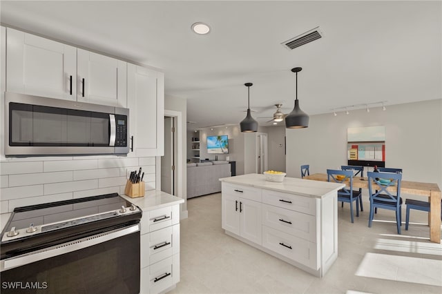 kitchen with light stone countertops, tasteful backsplash, pendant lighting, white cabinets, and appliances with stainless steel finishes