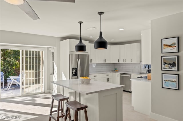 kitchen with backsplash, light stone countertops, light tile patterned floors, white cabinetry, and stainless steel appliances