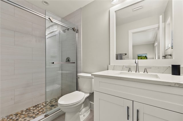 bathroom featuring vanity, toilet, and a shower with shower door