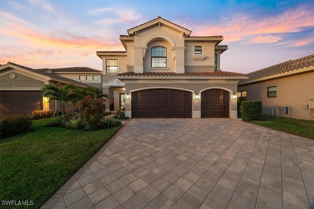 mediterranean / spanish home featuring a lawn and a garage