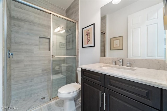 bathroom featuring vanity, toilet, and a shower with door