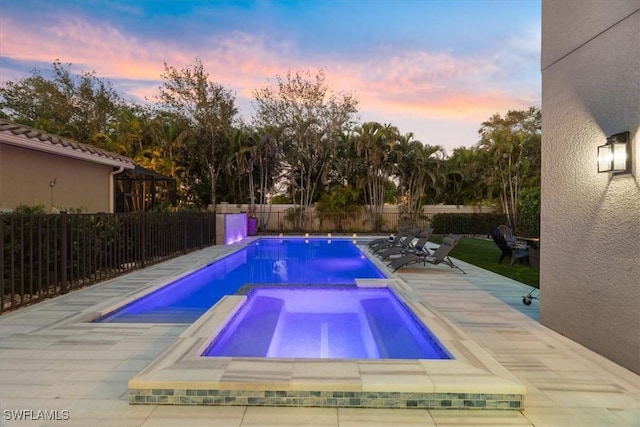 pool at dusk featuring an in ground hot tub