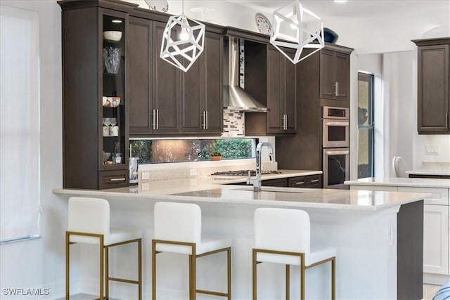 kitchen with decorative light fixtures, dark brown cabinetry, a breakfast bar area, and double oven