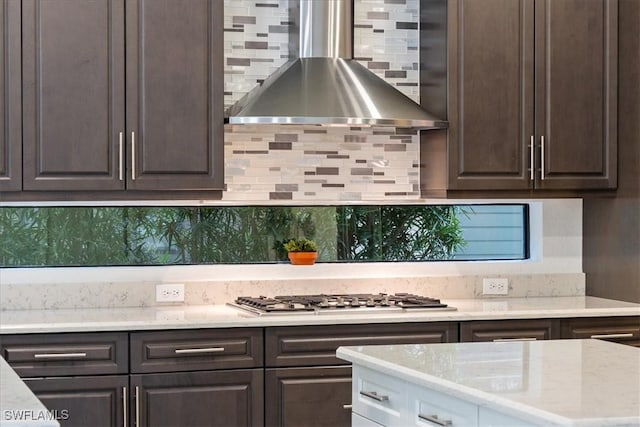 kitchen featuring decorative backsplash, dark brown cabinetry, stainless steel gas cooktop, and wall chimney range hood