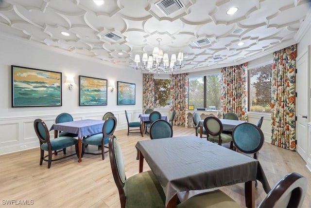 dining space featuring crown molding, light hardwood / wood-style flooring, and a chandelier