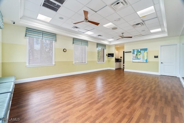 exercise room with hardwood / wood-style floors, a paneled ceiling, a raised ceiling, and ceiling fan