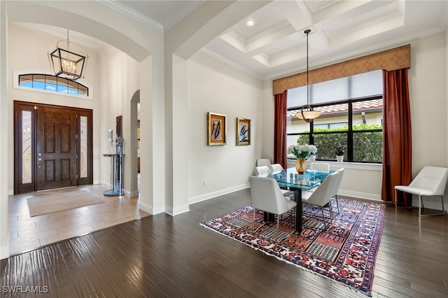 dining space with coffered ceiling, dark wood-type flooring, crown molding, an inviting chandelier, and beamed ceiling