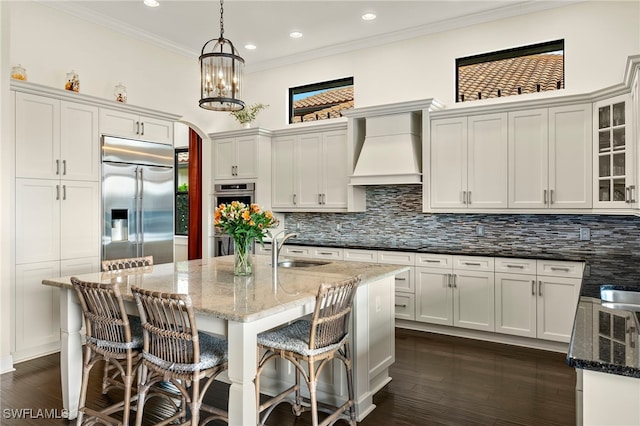 kitchen with dark stone counters, sink, custom exhaust hood, and appliances with stainless steel finishes