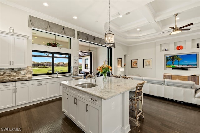 kitchen featuring light stone countertops, decorative backsplash, sink, hanging light fixtures, and a breakfast bar area