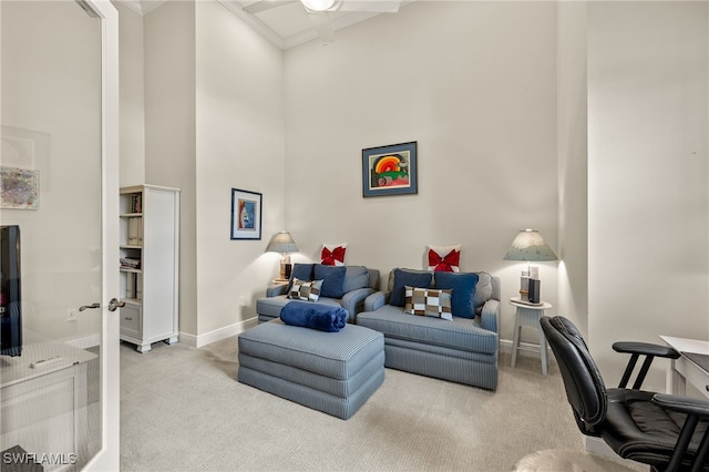 living room with carpet, a towering ceiling, ceiling fan, and ornamental molding