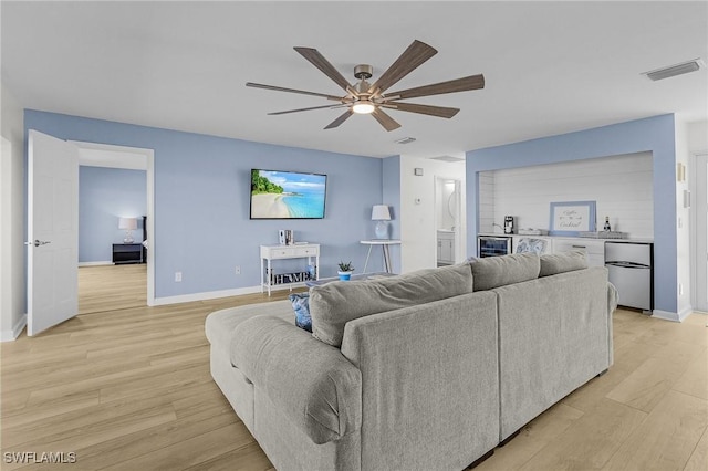 living room featuring ceiling fan, light wood-type flooring, and beverage cooler