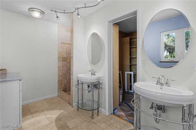 bathroom with double sink and tiled shower