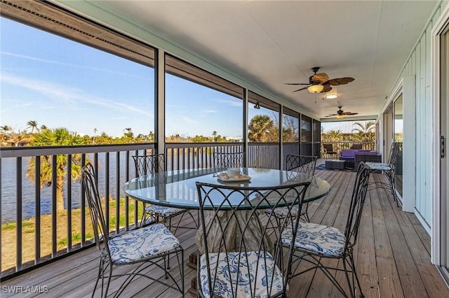 sunroom / solarium with ceiling fan and a water view