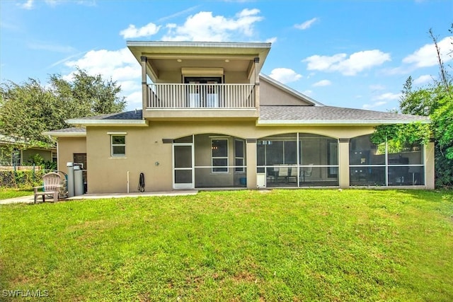 rear view of house with a patio, a balcony, a yard, and a sunroom