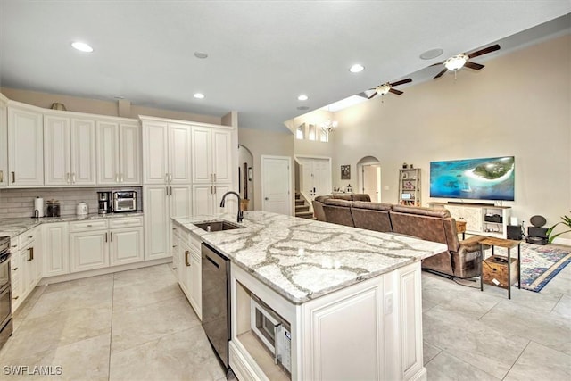 kitchen featuring sink, dishwasher, light stone countertops, white cabinets, and a center island with sink