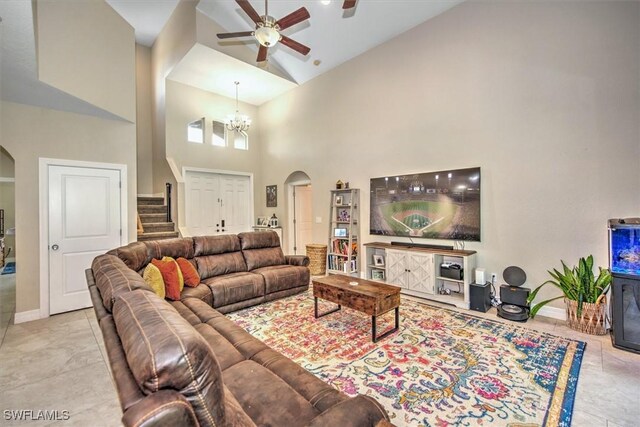 living room featuring ceiling fan with notable chandelier and a high ceiling