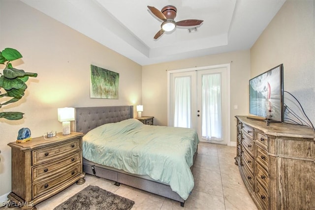 tiled bedroom featuring french doors and a raised ceiling