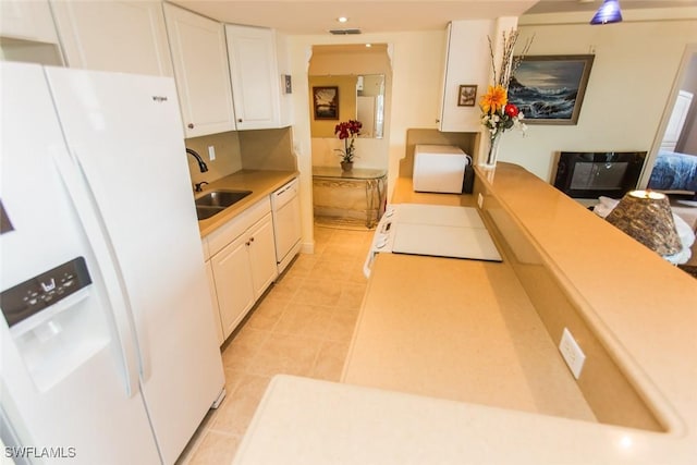 kitchen with white appliances, sink, light tile patterned floors, and white cabinetry