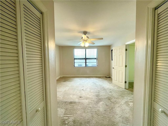 unfurnished bedroom featuring ceiling fan, light colored carpet, and a closet