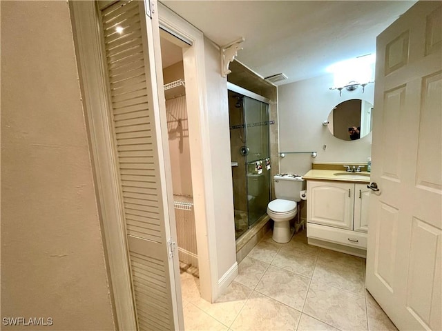 bathroom with toilet, vanity, a shower with shower door, and tile patterned floors