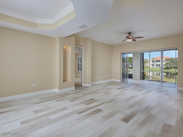 empty room featuring ceiling fan, light hardwood / wood-style floors, a raised ceiling, and ornamental molding