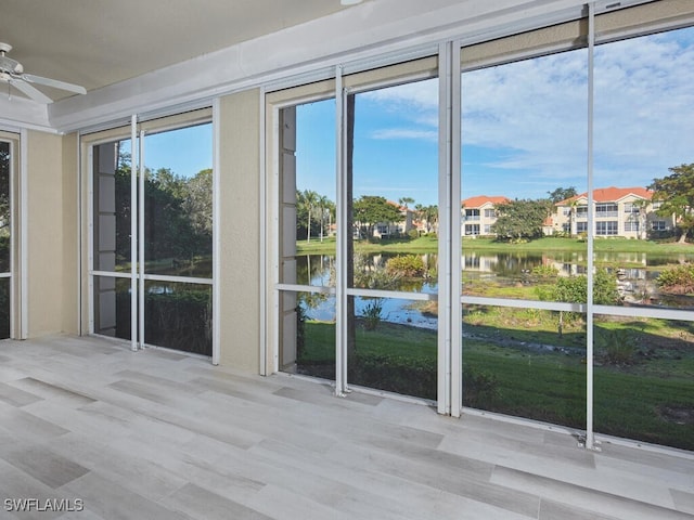 unfurnished sunroom featuring ceiling fan, a healthy amount of sunlight, and a water view