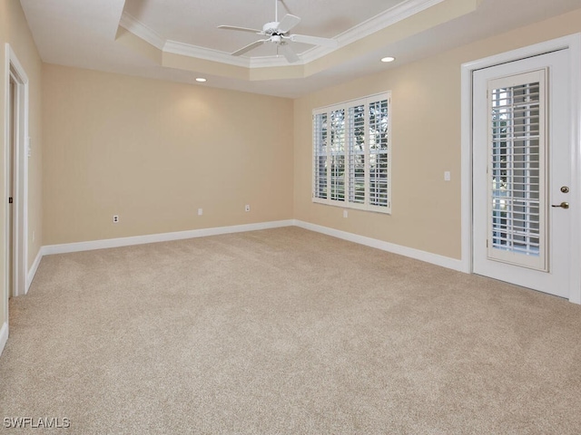 unfurnished room with ceiling fan, crown molding, light carpet, and a tray ceiling