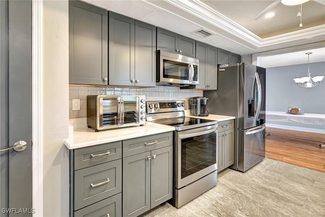 kitchen featuring ornamental molding, stainless steel appliances, and gray cabinetry