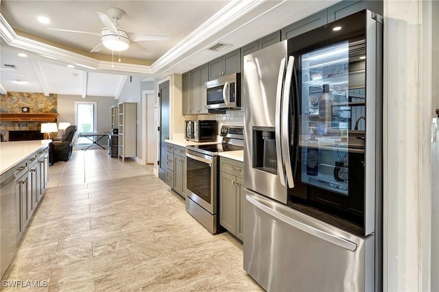 kitchen featuring crown molding, ceiling fan, appliances with stainless steel finishes, gray cabinetry, and a tray ceiling