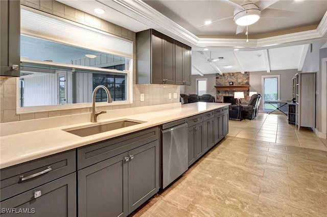 kitchen featuring sink, stainless steel dishwasher, ceiling fan, a fireplace, and backsplash