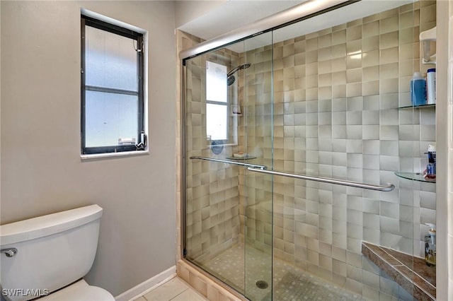 bathroom with tile patterned flooring, a shower with shower door, and toilet