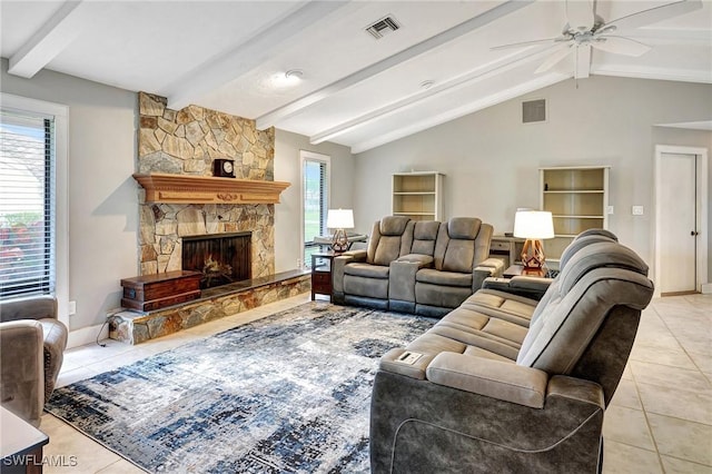 tiled living room with ceiling fan, vaulted ceiling with beams, and a fireplace