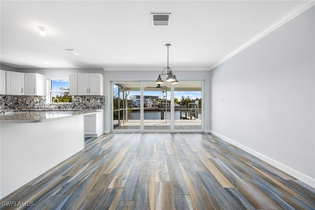 unfurnished dining area featuring a water view, ornamental molding, sink, and hardwood / wood-style flooring