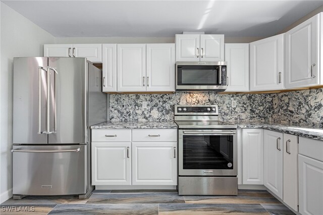 kitchen featuring light stone counters, stainless steel appliances, and white cabinets