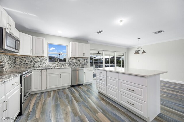 kitchen featuring stainless steel appliances, decorative light fixtures, white cabinets, and decorative backsplash