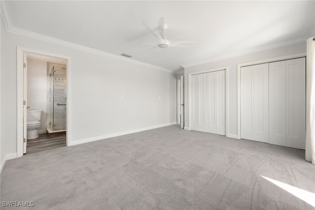 unfurnished bedroom with ensuite bathroom, light colored carpet, ceiling fan, multiple closets, and crown molding