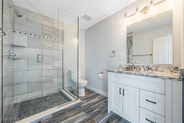 bathroom featuring vanity, a shower with shower door, and toilet