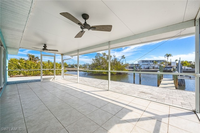 view of patio with a water view, ceiling fan, and a dock