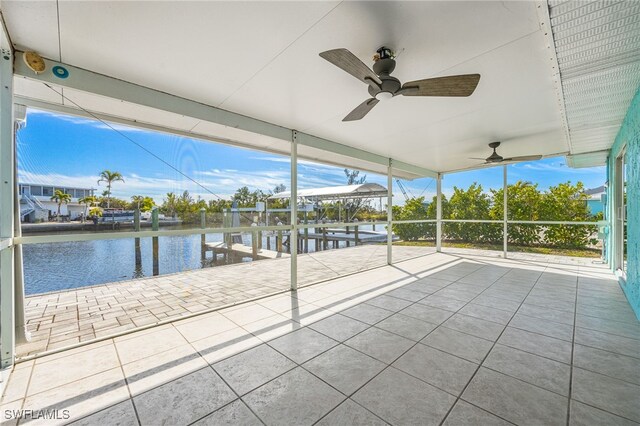 unfurnished sunroom featuring a water view, ceiling fan, and a wealth of natural light