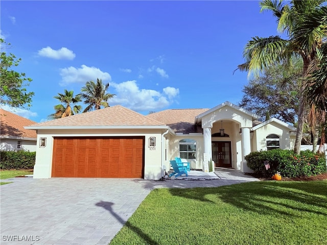 view of front of house featuring stucco siding, a front lawn, decorative driveway, and a garage