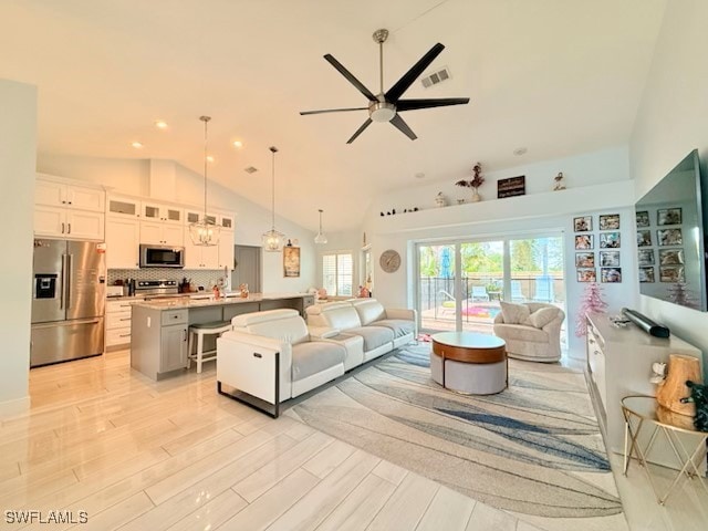 living room featuring ceiling fan, visible vents, high vaulted ceiling, light wood finished floors, and recessed lighting