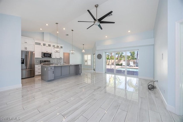 kitchen with stainless steel appliances, decorative light fixtures, white cabinetry, glass insert cabinets, and a large island with sink