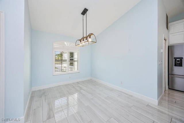 unfurnished dining area featuring light wood-type flooring, lofted ceiling, baseboards, and an inviting chandelier