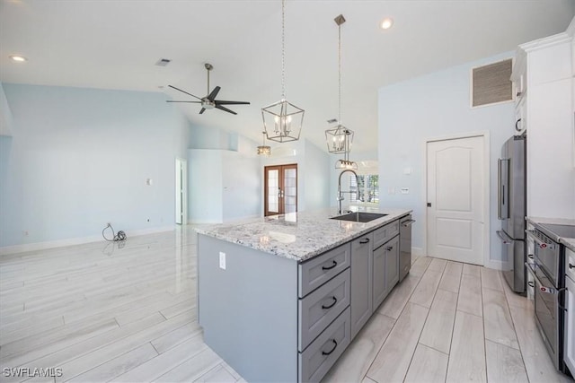 kitchen with visible vents, a sink, pendant lighting, stainless steel appliances, and a center island with sink