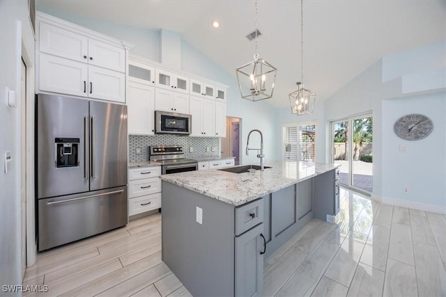 kitchen with stainless steel appliances, white cabinets, a sink, and glass insert cabinets