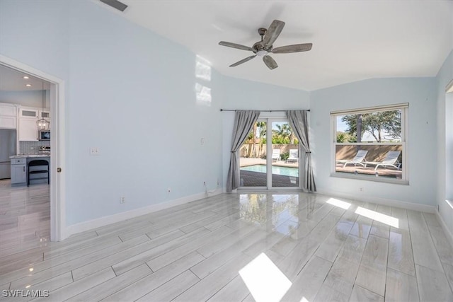 spare room featuring vaulted ceiling, ceiling fan, light wood-style flooring, and baseboards